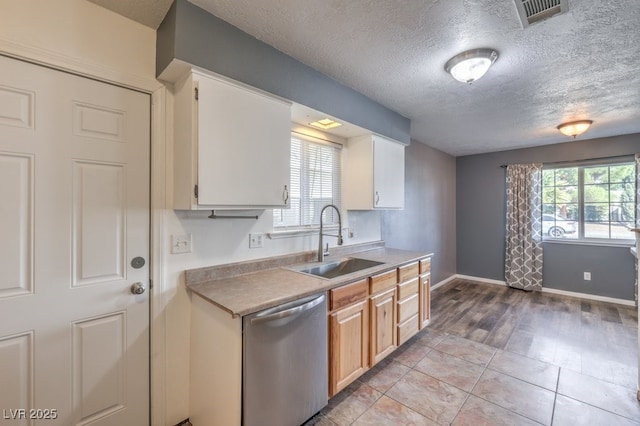 kitchen featuring stainless steel dishwasher, a textured ceiling, sink, light tile patterned floors, and white cabinetry