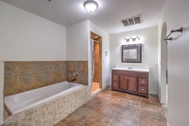 bathroom with plus walk in shower, a textured ceiling, and vanity