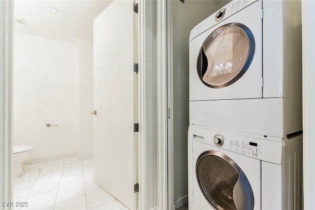 clothes washing area featuring light tile patterned floors and stacked washer and clothes dryer