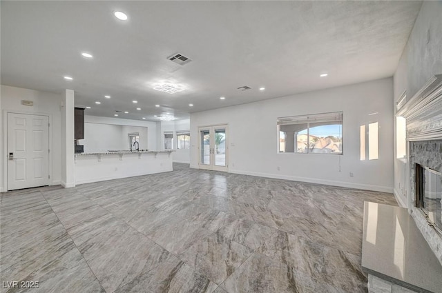 unfurnished living room featuring a healthy amount of sunlight, sink, and french doors