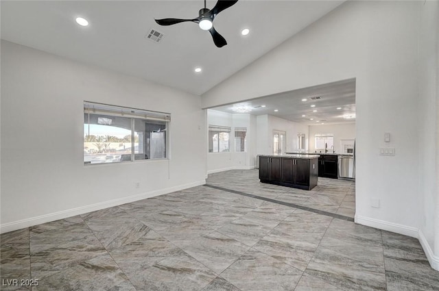 unfurnished living room with ceiling fan, sink, and vaulted ceiling