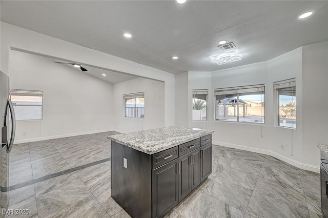 kitchen with plenty of natural light, a center island, and light stone counters