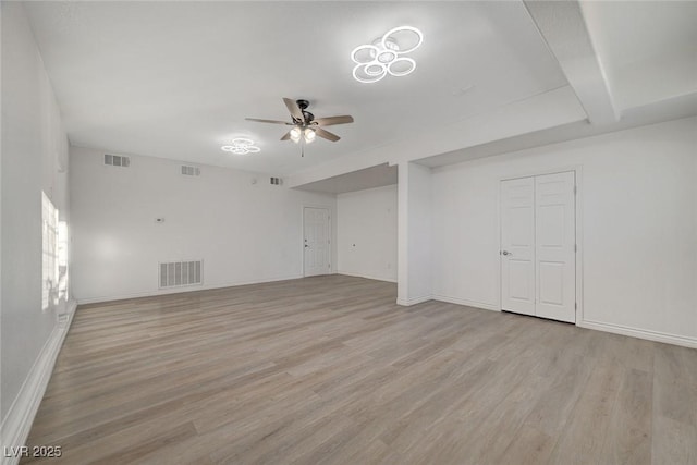 spare room with beam ceiling, light hardwood / wood-style floors, and ceiling fan