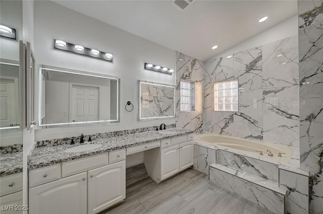 bathroom featuring vanity and tiled bath