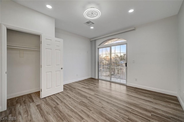 unfurnished bedroom featuring hardwood / wood-style flooring, access to exterior, and a closet