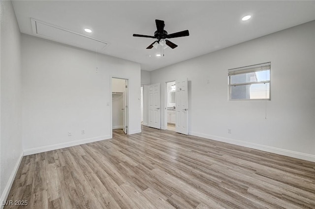 unfurnished bedroom with ensuite bath, ceiling fan, light hardwood / wood-style flooring, a spacious closet, and a closet