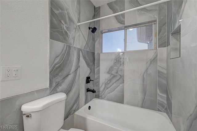 bathroom featuring tiled shower / bath combo and toilet