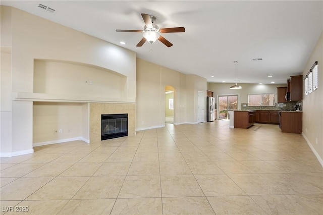 unfurnished living room featuring a tile fireplace, ceiling fan, and light tile patterned floors