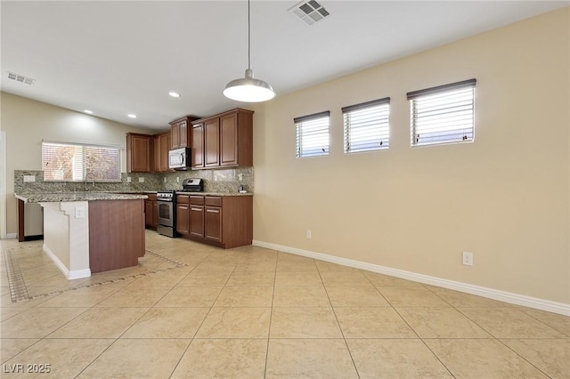 kitchen with decorative light fixtures, stainless steel range, light tile patterned floors, and light stone counters