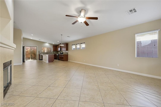 unfurnished living room featuring light tile patterned flooring, a tile fireplace, ceiling fan, and vaulted ceiling