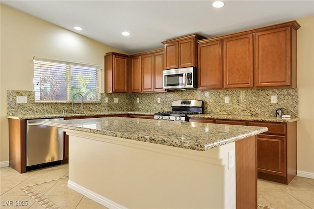 kitchen featuring stainless steel appliances, sink, light stone counters, light tile patterned floors, and a kitchen island