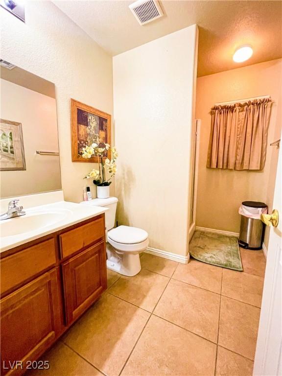 bathroom featuring tile patterned flooring, vanity, toilet, a shower with door, and a textured ceiling