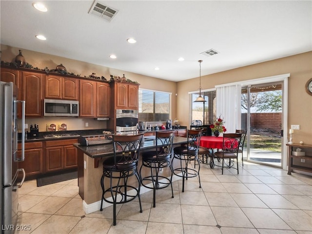 kitchen featuring a center island, decorative light fixtures, stainless steel appliances, a breakfast bar, and light tile patterned floors