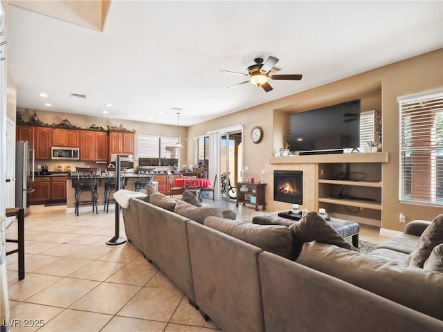 living room featuring ceiling fan, light tile patterned floors, and a fireplace