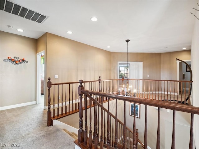 hall featuring carpet and an inviting chandelier