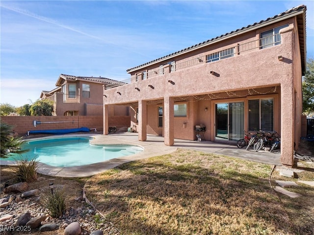 back of house with a covered pool, a yard, and a patio