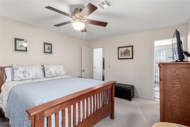 bedroom with ceiling fan, light colored carpet, and a textured ceiling