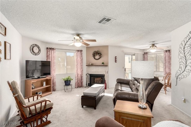 living room featuring light colored carpet, ceiling fan, and a tiled fireplace