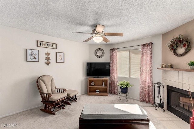 living room with ceiling fan, a textured ceiling, a tile fireplace, and light carpet