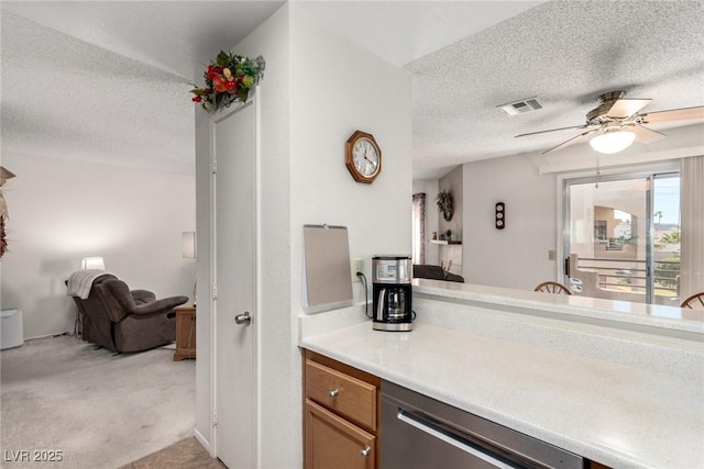 kitchen with stainless steel dishwasher, ceiling fan, light carpet, and a textured ceiling