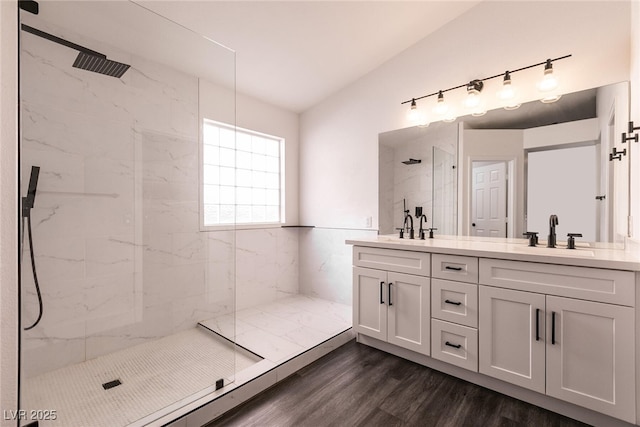 bathroom with lofted ceiling, a tile shower, vanity, and hardwood / wood-style floors