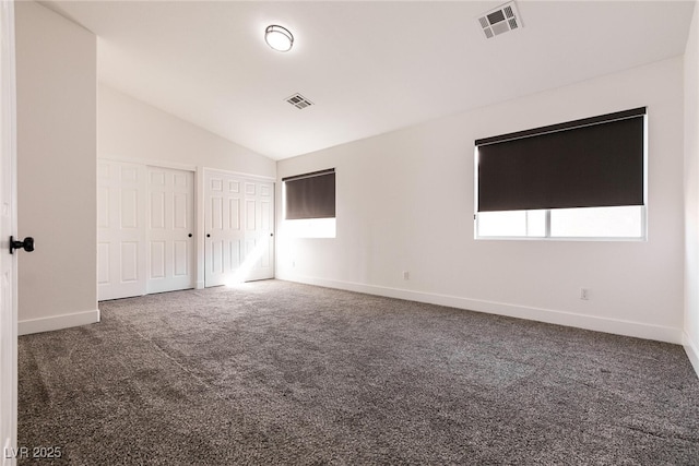 empty room featuring vaulted ceiling and dark colored carpet