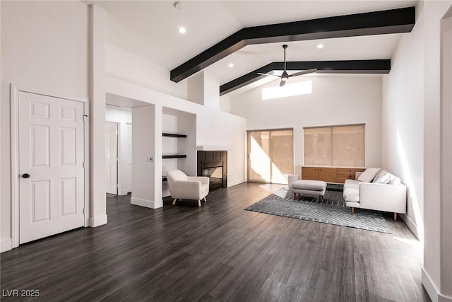 unfurnished living room with built in features, dark hardwood / wood-style flooring, a tiled fireplace, ceiling fan, and beamed ceiling