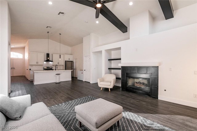 living room featuring a tiled fireplace, ceiling fan, high vaulted ceiling, dark hardwood / wood-style floors, and sink