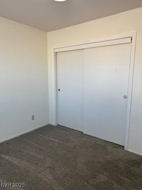 unfurnished bedroom featuring a closet and dark colored carpet