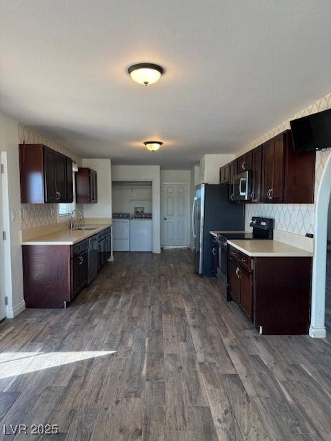 kitchen featuring backsplash, hardwood / wood-style flooring, washer and dryer, dark brown cabinetry, and stainless steel appliances