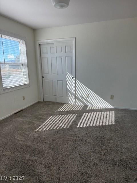 unfurnished bedroom with dark colored carpet and a closet