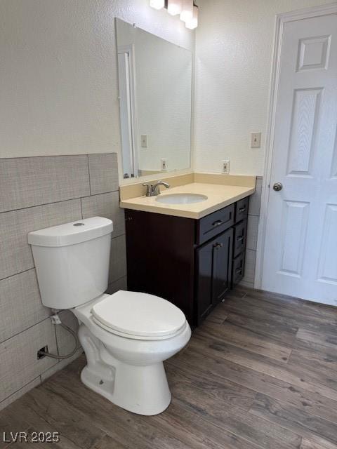 bathroom featuring hardwood / wood-style floors, vanity, toilet, and tile walls