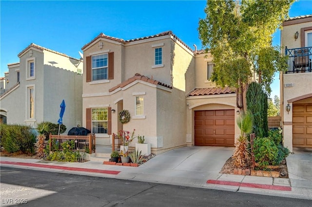 mediterranean / spanish house with a garage, concrete driveway, a tile roof, and stucco siding