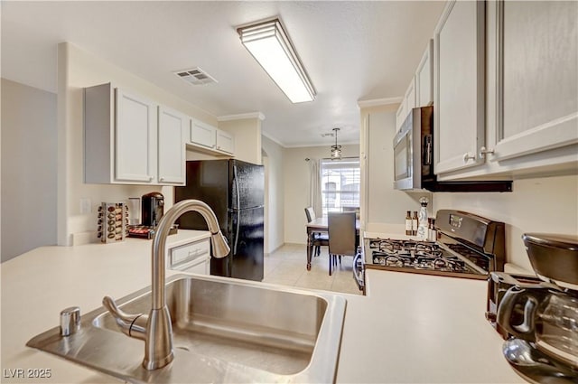 kitchen with sink, range, black refrigerator, ornamental molding, and white cabinets