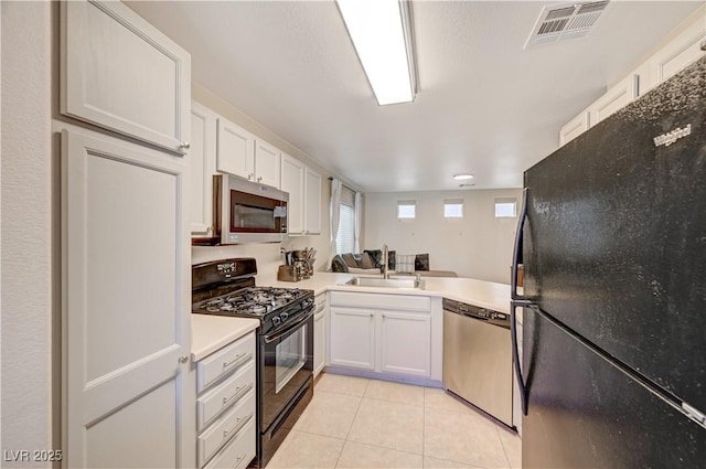 kitchen featuring sink, black appliances, white cabinets, and light tile patterned flooring