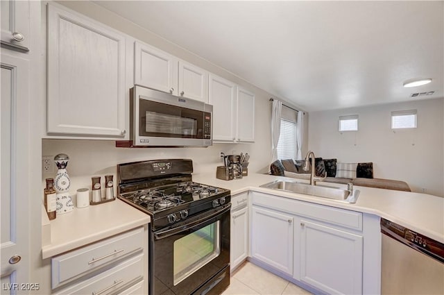 kitchen featuring sink, white cabinetry, light tile patterned floors, appliances with stainless steel finishes, and kitchen peninsula