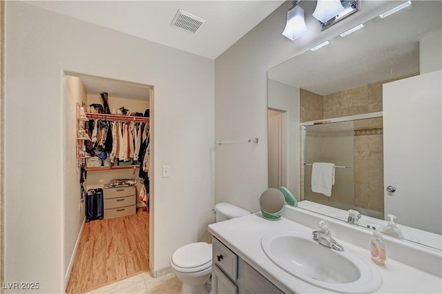 bathroom featuring a shower with door, vanity, tile patterned floors, and toilet