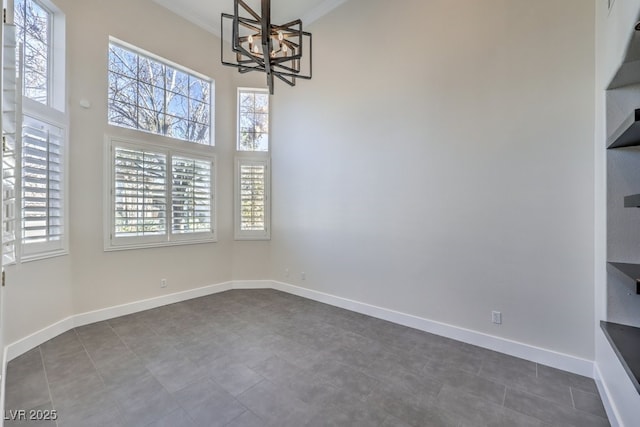 unfurnished dining area with dark tile patterned flooring, crown molding, and a chandelier