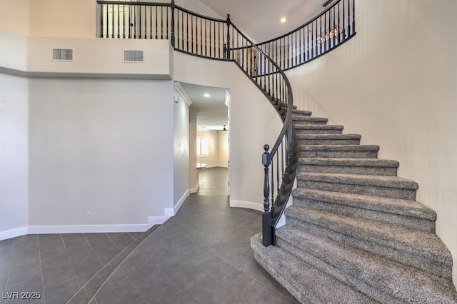 staircase featuring tile patterned flooring and a towering ceiling