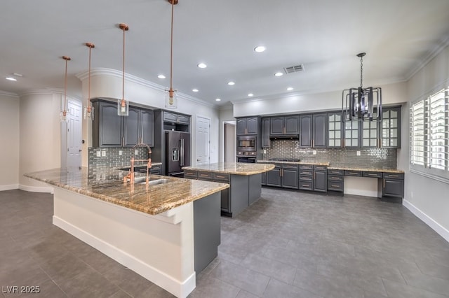 kitchen featuring sink, light stone countertops, decorative light fixtures, kitchen peninsula, and stainless steel appliances