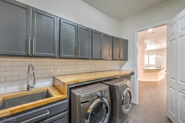 laundry area with cabinets, tile patterned flooring, washer and clothes dryer, and sink