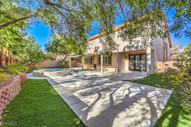 back of house with a pool with hot tub, a patio, and french doors