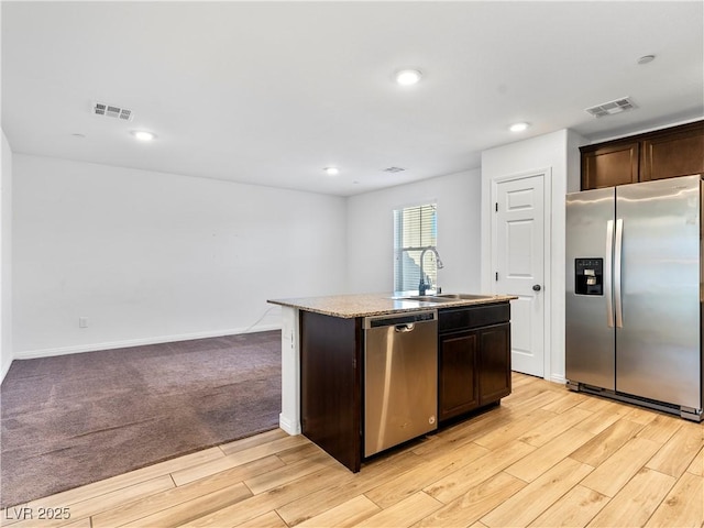 kitchen with a center island with sink, appliances with stainless steel finishes, and dark brown cabinetry