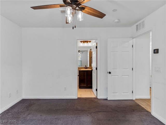 empty room featuring sink, ceiling fan, and carpet