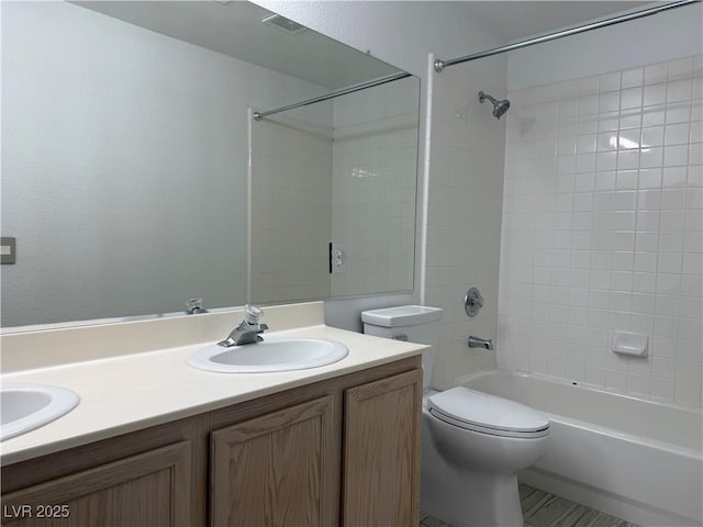 full bathroom featuring vanity, tiled shower / bath combo, and toilet