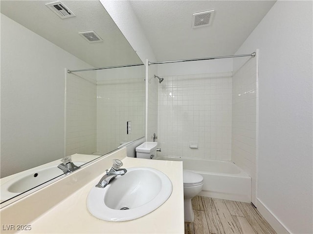 full bathroom with tiled shower / bath, vanity, and toilet