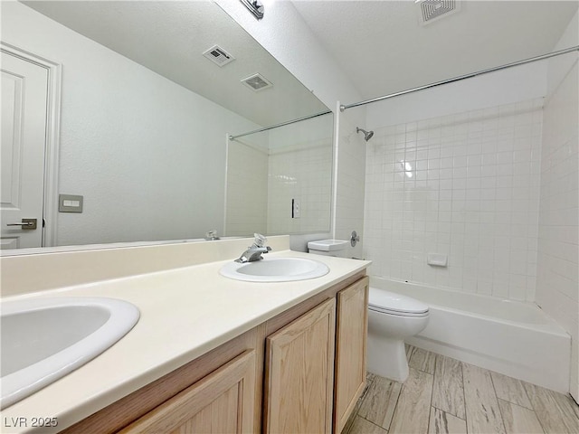 full bathroom featuring vanity, tiled shower / bath, and toilet