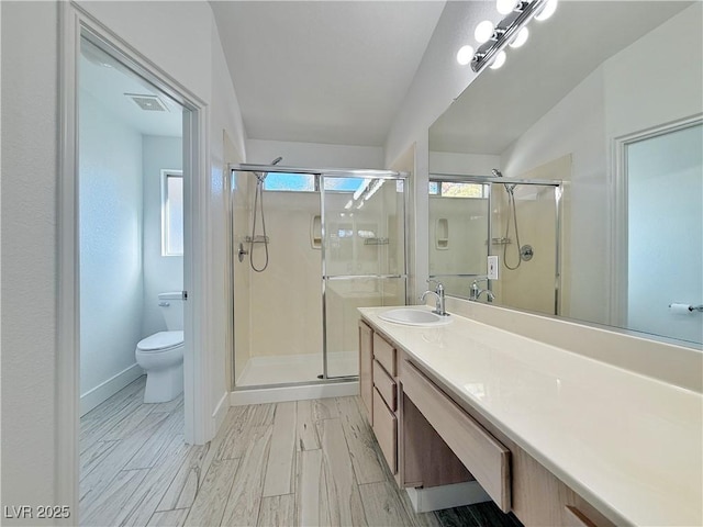 bathroom featuring a shower with door, vanity, and toilet