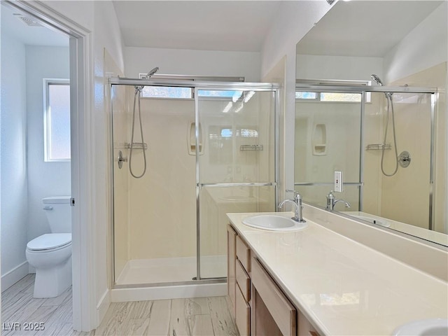 bathroom with a healthy amount of sunlight, vanity, toilet, and an enclosed shower