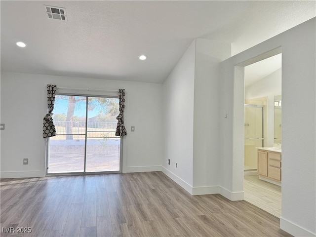 empty room with lofted ceiling and light hardwood / wood-style floors